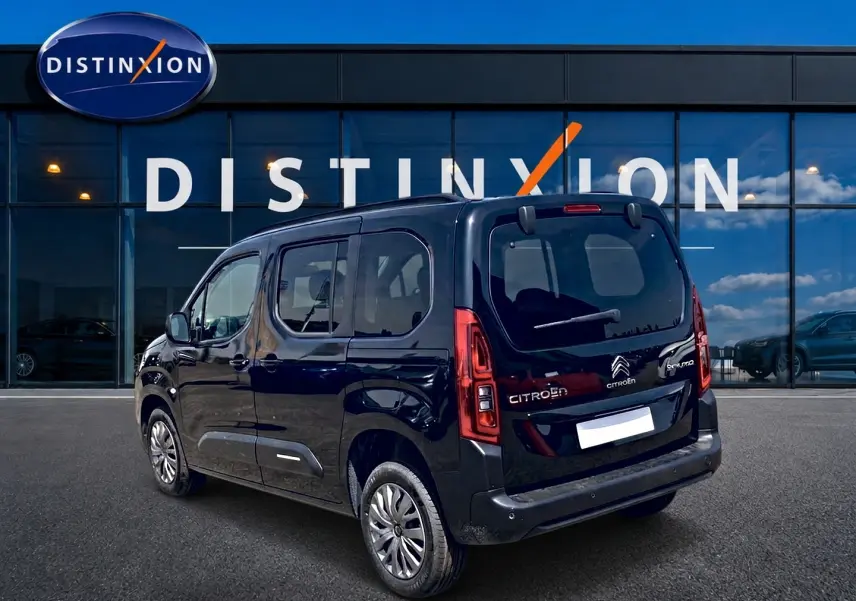 Citroën Berlingo noir vu en 3/4 arrière droit, avec vitres teintées et barres de toit visibles.