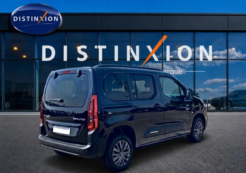 Vue 3/4 arrière droite du Citroën Berlingo noir stationné devant une vitrine avec logo Distinxion.