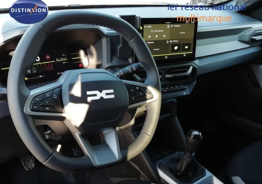 Vue intérieure du tableau de bord et volant du Dacia Duster 2026 avec boîte manuelle, finition gris noir et écran tactile central.