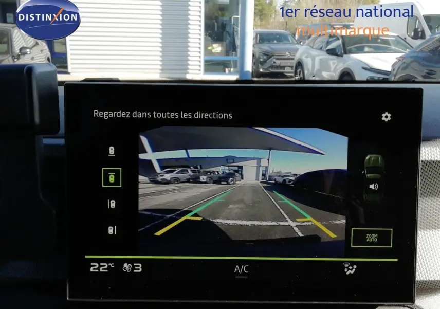 Écran de caméra de recul montrant un parking avec plusieurs véhicules, vue arrière du Dacia Duster gris schiste métal.
