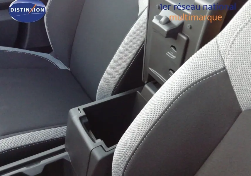 Vue rapprochée de l’intérieur du Dacia Duster 2026, montrant l’accoudoir central ouvert et les sièges tissu gris clair et noir.