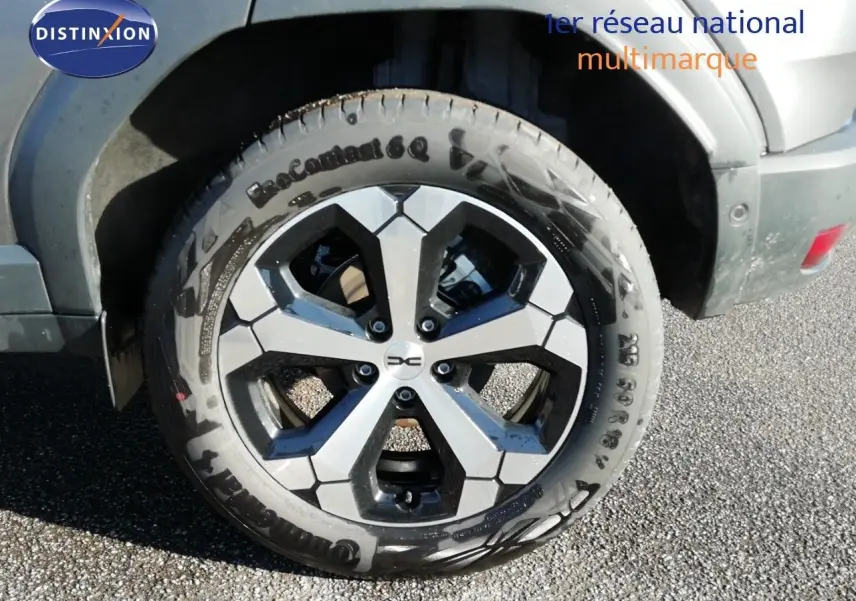 Gros plan sur la roue avant droite du Dacia Duster gris schiste métal avec jante alliage bicolore.
