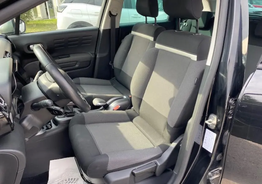 Intérieur avant du Citroën C3 Aircross noir, sièges tissu gris et noir, volant en croûte de cuir visible côté conducteur.