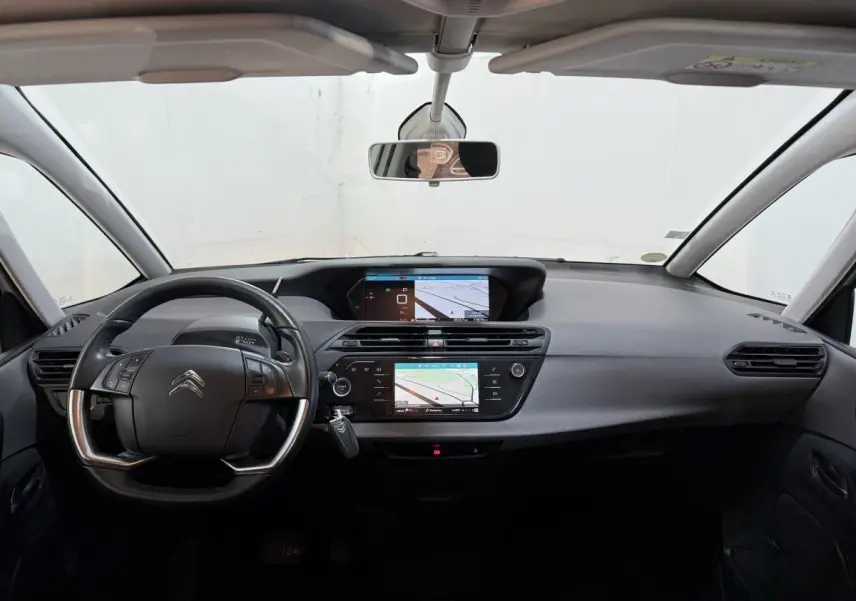Vue intérieure avant du tableau de bord noir du Citroën Grand C4 Spacetourer blanc avec double écran tactile et volant multifonctions.
