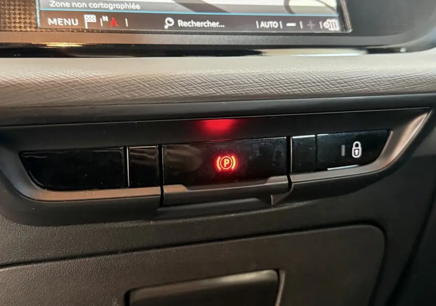 Gros plan sur le tableau de bord noir du Citroën Grand C4 Spacetourer 2021, bouton frein à main électrique allumé en rouge.