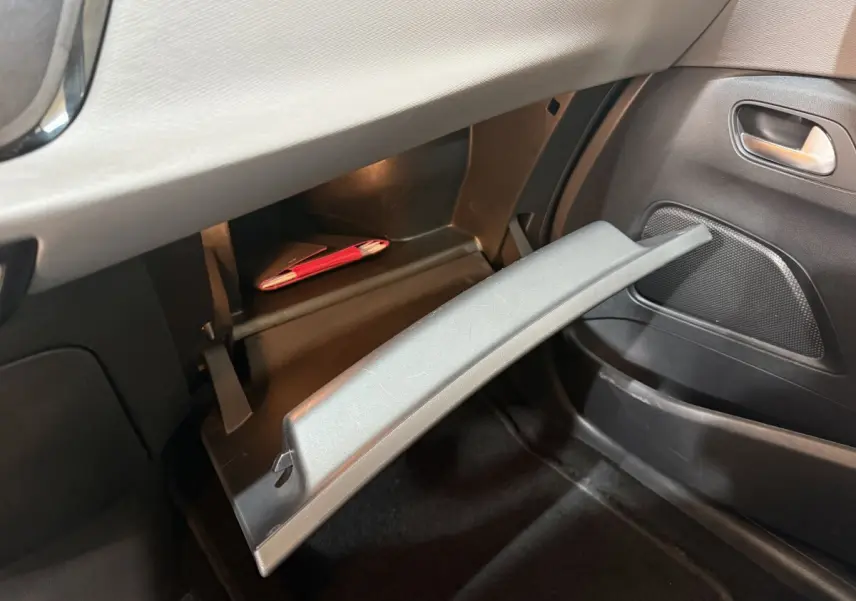 Ouverture de la boîte à gants côté passager dans l'habitacle noir du Citroën Grand C4 Spacetourer blanc 2021.