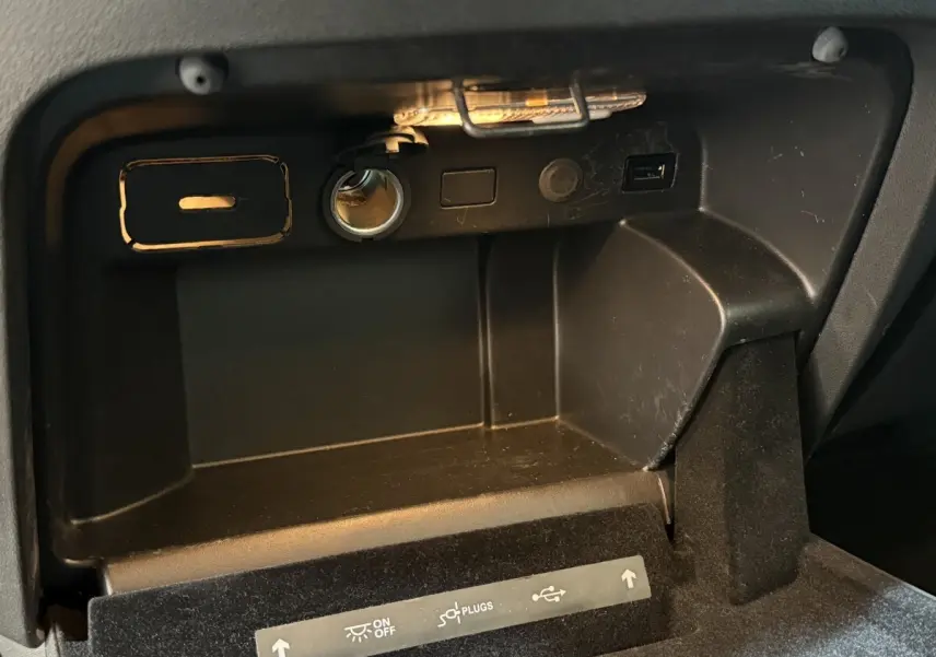Gros plan sur la boîte à gants noire du Citroën Grand C4 Spacetourer avec prise 12V et port USB visibles.