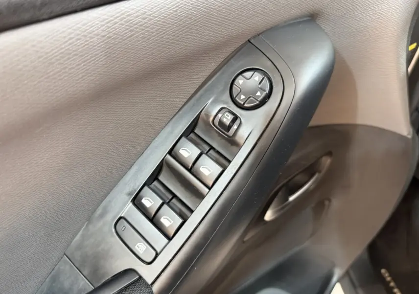 Gros plan sur les commandes des vitres et rétroviseurs côté conducteur du Citroën Grand C4 Spacetourer blanc, intérieur noir.