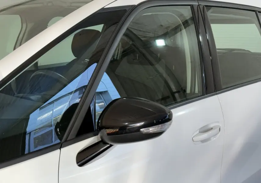 Gros plan sur la porte avant gauche blanche du Citroën Grand C4 Spacetourer avec rétroviseur noir brillant et poignée intégrée.