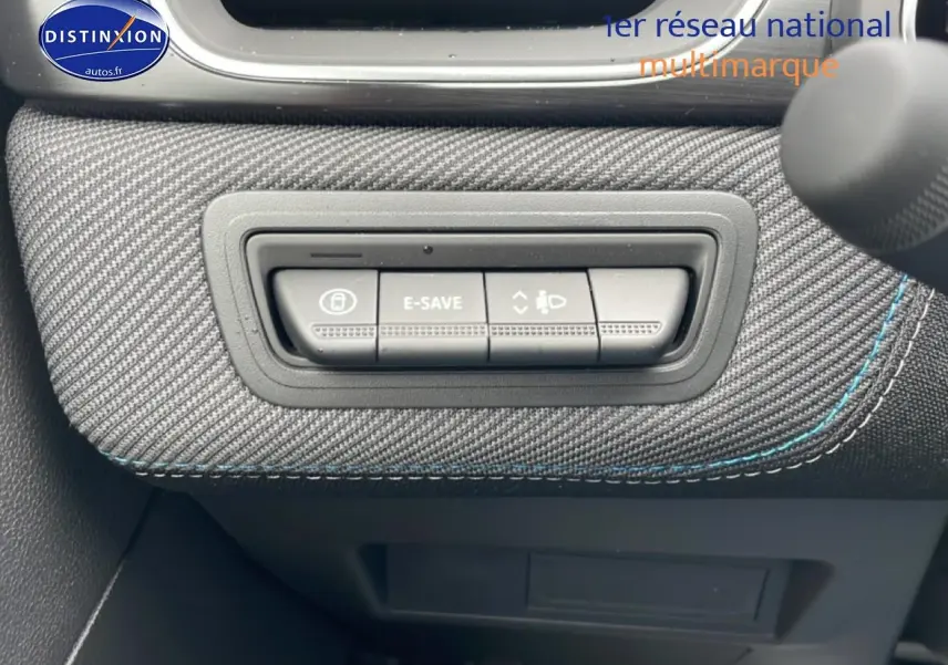Gros plan sur les commandes E-Save et réglage des phares sur tableau de bord en tissu gris avec surpiqûres bleues.