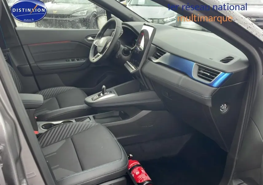 Intérieur avant droit du Renault Captur gris cassiopée avec tableau de bord noir et inserts bleus esprit Alpine.