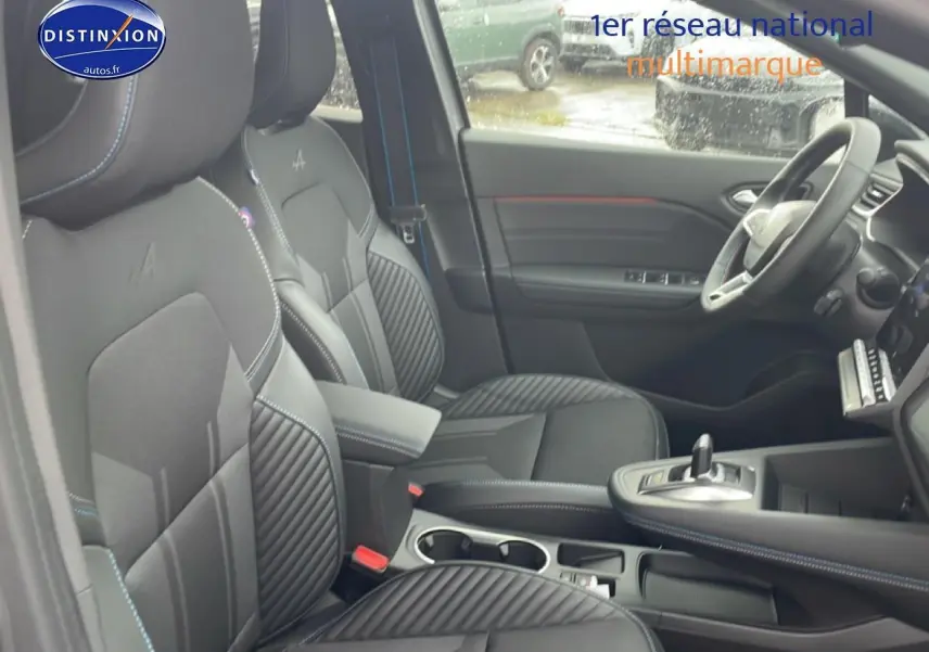 Vue intérieure côté conducteur du Renault Captur 1.8 e-tech hybride, sièges noirs esprit Alpine avec surpiqûres bleues.