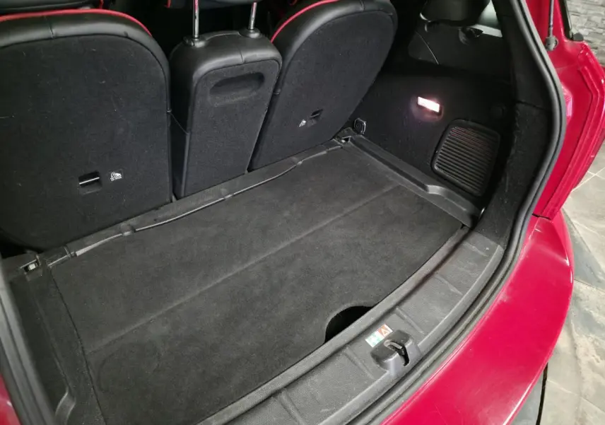 Vue arrière du coffre ouvert d'une MINI Countryman John Cooper Works rouge, montrant l'espace de chargement noir.