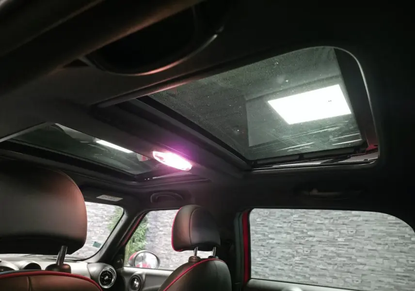 Vue intérieure du toit ouvrant en verre du MINI Countryman John Cooper Works rouge, avec sièges avant en cuir noir.