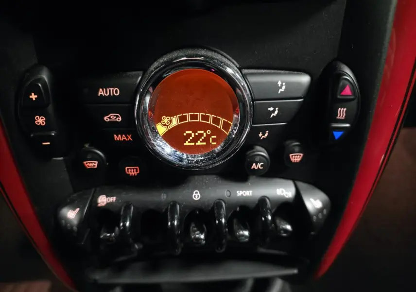 Gros plan sur la console centrale rouge du MINI John Cooper Works avec affichage digital de la climatisation à 22°C.