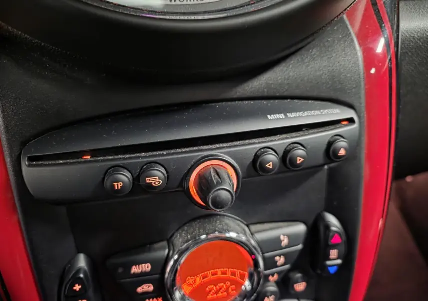 Gros plan sur la console centrale rouge et noire du MINI John Cooper Works avec commandes de climatisation et navigation.
