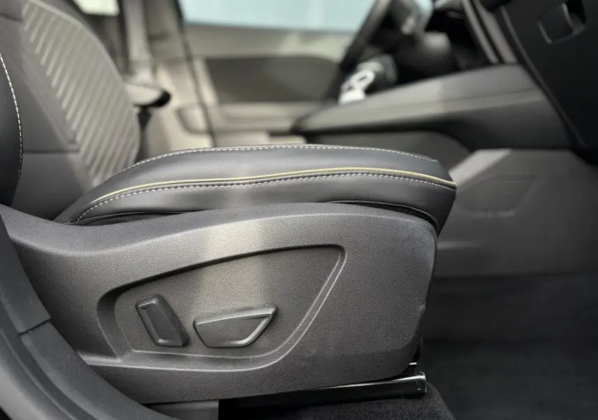 Détail du siège conducteur noir avec réglages électriques et surpiqûres contrastantes dans l’habitacle Renault Symbioz.