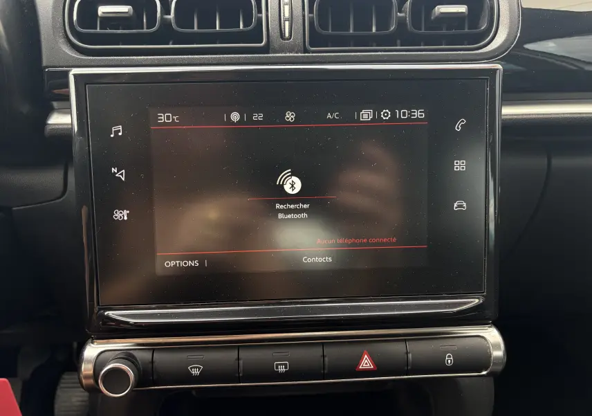 Vue rapprochée de l’écran tactile central noir du tableau de bord d’une Citroën C3 blanche de 2019, affichant la recherche Bluetooth.
