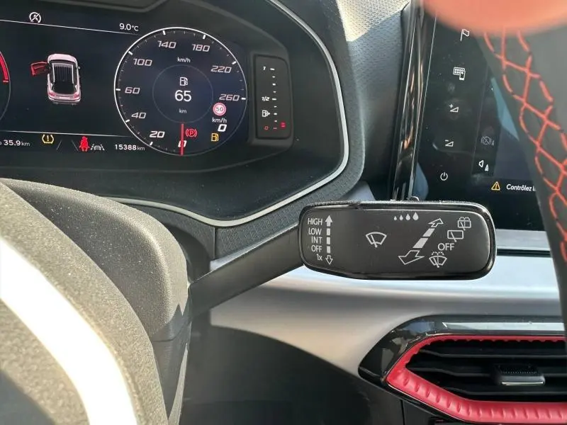 Gros plan sur le commodo d’essuie-glace du tableau de bord du SEAT Arona 2025, volant avec surpiqûres rouges visible.