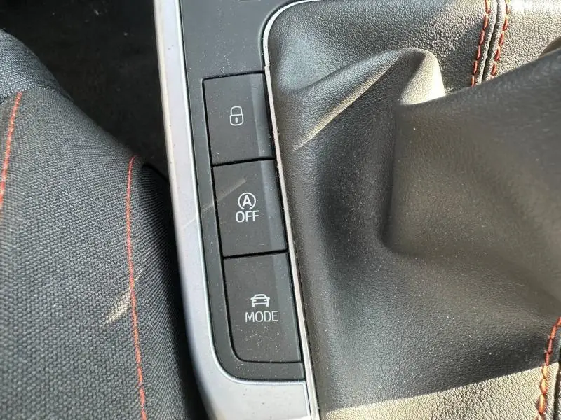 Vue rapprochée de la console centrale du SEAT Arona 2025, boutons de modes de conduite et coutures rouges sur tissu noir.