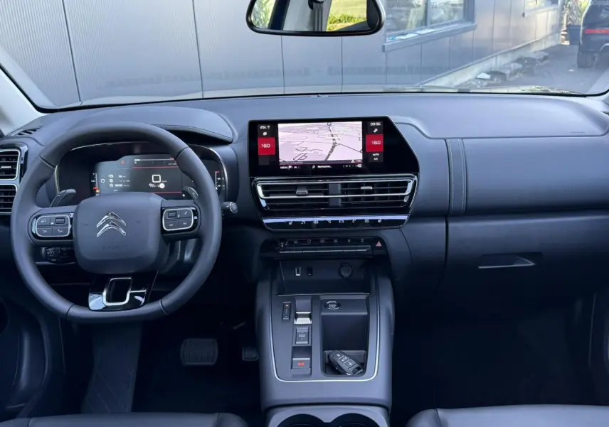 Tableau de bord et console centrale noirs du Citroën C5 Aircross 2025, avec écran tactile GPS et volant multifonction.
