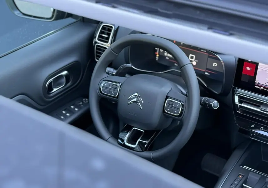 Vue intérieure du volant cuir noir et tableau de bord numérique du Citroën C5 Aircross 2025 avec écran tactile et commandes intégrées.
