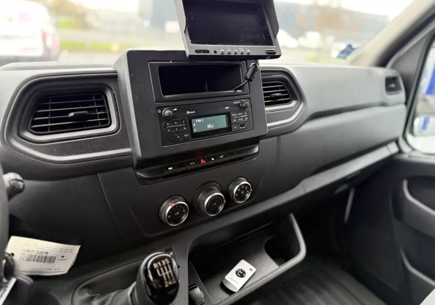 Vue intérieure côté passager du tableau de bord noir du Nissan NV400 Fourgon 2020 avec commande manuelle et écran intégré.