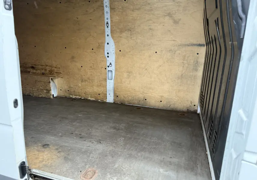 Vue intérieure arrière du fourgon blanc Nissan NV400 Optima 2020, montrant la zone de chargement en bois usé.