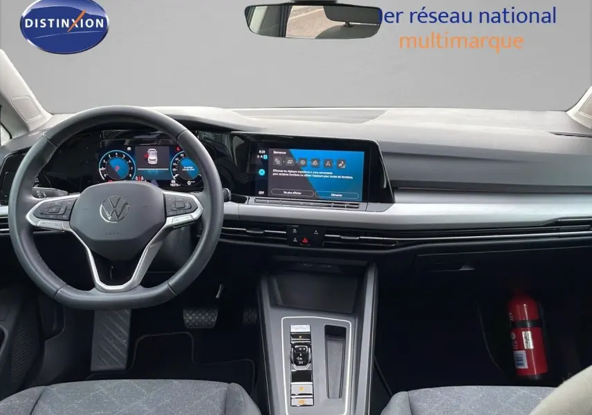 Vue intérieure avant du tableau de bord et volant d'une Volkswagen Golf VIII bleu lapiz metal avec écran tactile et commandes modernes.