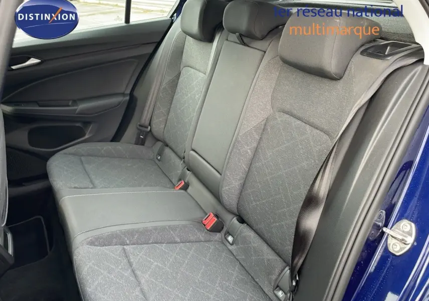 Vue intérieure sur les sièges arrière en tissu gris de la Volkswagen Golf VIII bleu lapiz metal avec ceinture de sécurité.