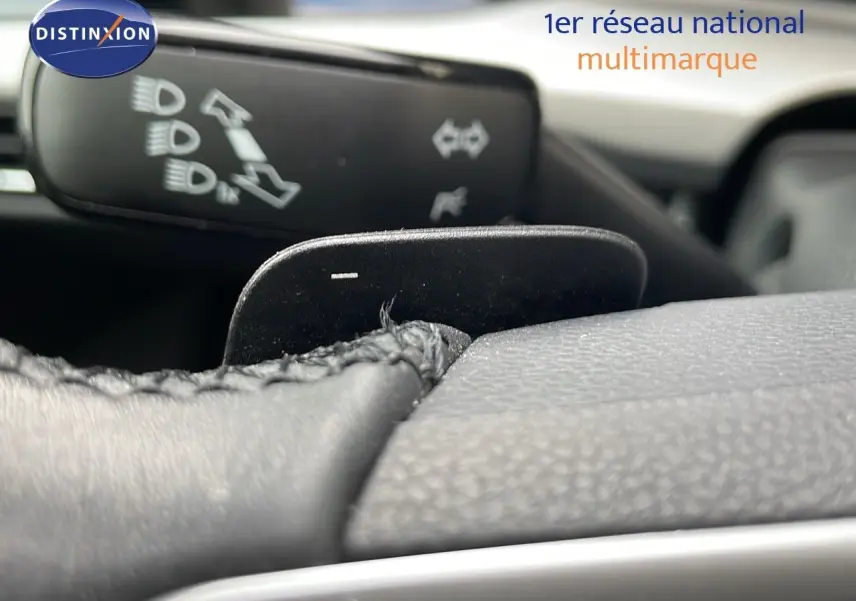 Gros plan sur la palette de changement de vitesses au volant d'une Volkswagen Golf VIII, intérieur noir texturé.