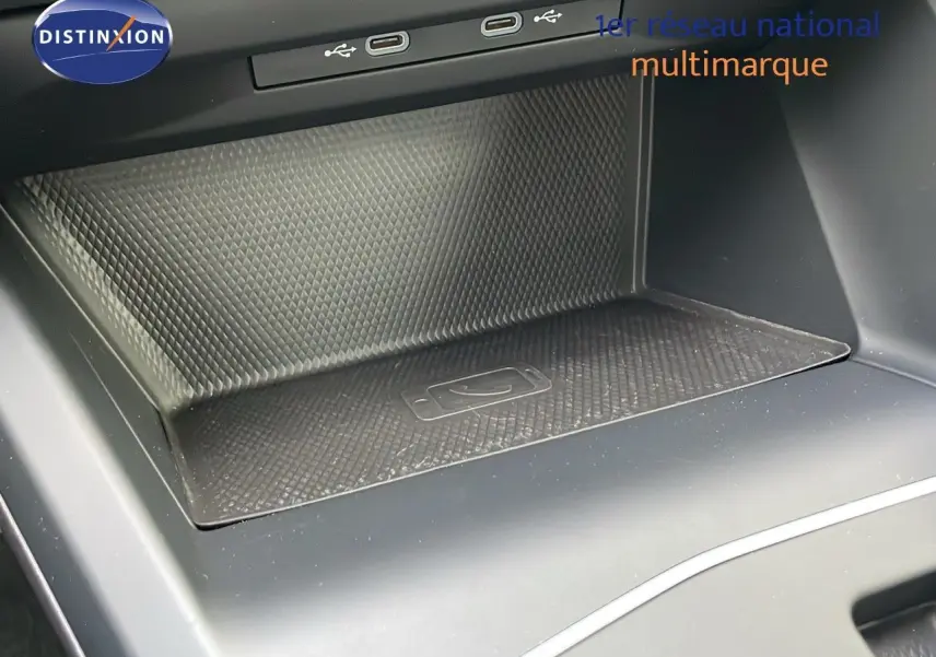 Gros plan sur la console centrale avec zone de recharge sans fil et ports USB d'une Volkswagen Golf VIII bleu lapiz metal.