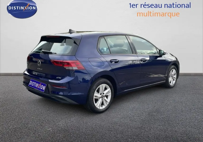 Vue 3/4 arrière droite d'une Volkswagen Golf VIII bleu lapiz metal, avec jantes alliage et cinq portes visibles.