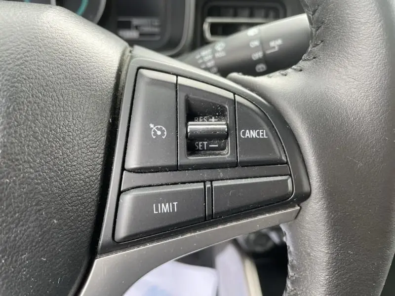 Gros plan sur les commandes de régulateur de vitesse au volant cuir noir du Suzuki Ignis gris foncé 2020.
