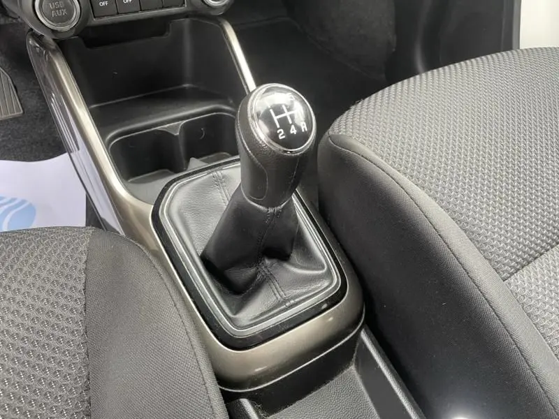 Le levier de vitesse manuel noir de la Suzuki Ignis 2020, vue rapprochée de la console centrale et des sièges gris foncé.