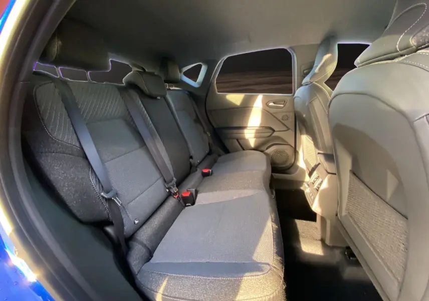 Vue intérieure arrière côté gauche du Renault Captur 2025 bleu Iron avec sièges tissu et toit noir visible.