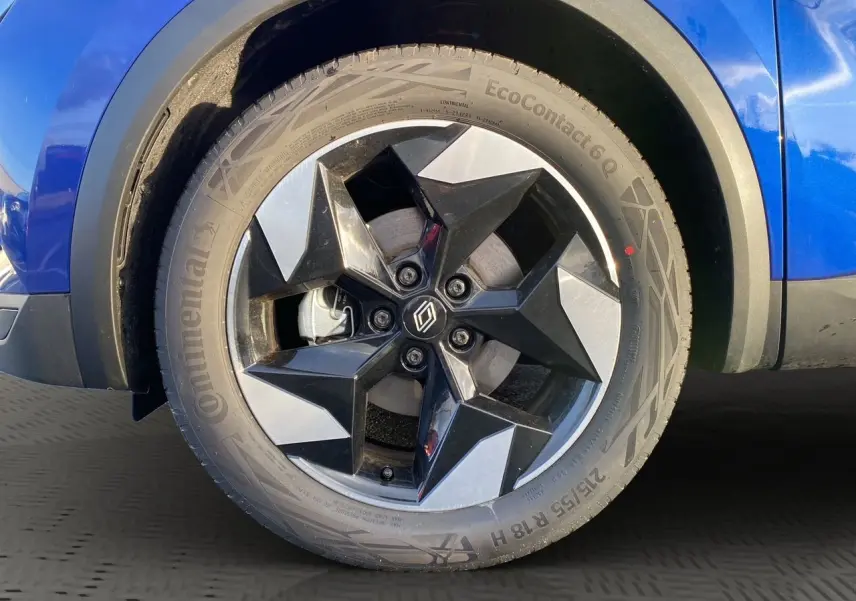 Gros plan sur la roue avant droite du Renault Captur bleu Iron 2025 avec jante noire et argentée au design géométrique.