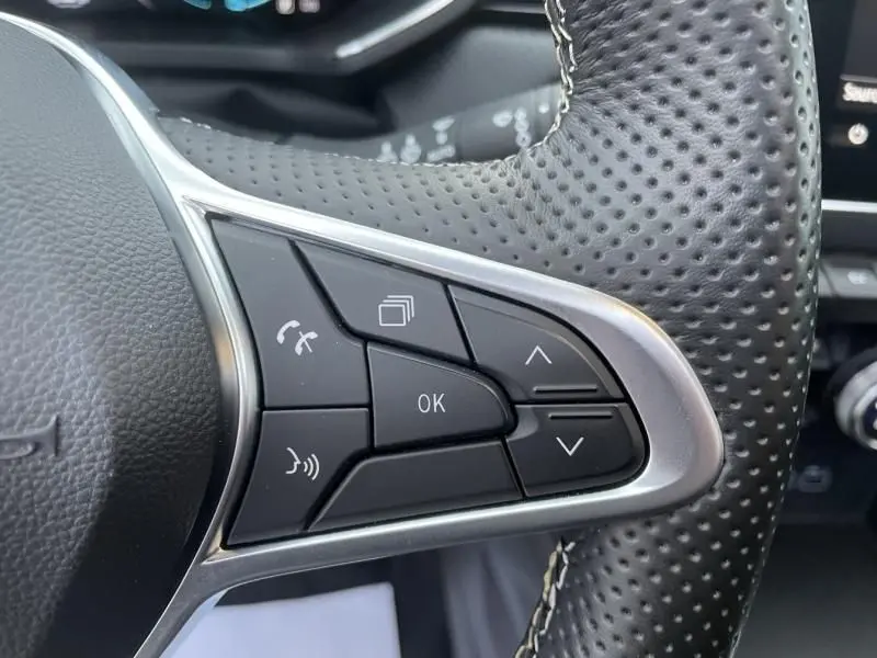 Gros plan sur les commandes au volant côté gauche du Renault Captur blanc nacré 2023, version hybride 1.6 E-Tech.