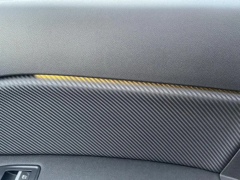 Détail intérieur montrant la garniture en fibre de carbone noire avec surpiqûres jaunes du Renault Captur 1.6 E-Tech hybride 2023.