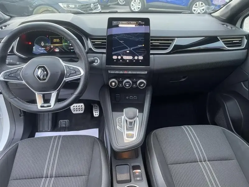 Vue intérieure avant du Renault Captur 1.6 E-Tech hybride 2023, tableau de bord avec écran tactile central et volant multifonction.