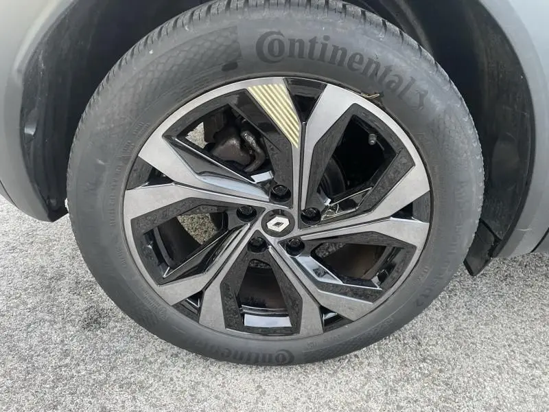 Gros plan sur la jante noire et argentée du Renault Captur blanc nacré 2023, avec logo Renault au centre.