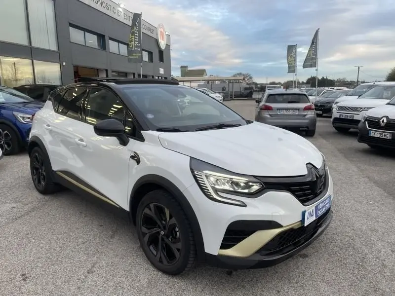 Renault Captur 1.6 E-Tech hybride blanc nacré en 3/4 avant droit, avec jantes noires et détails dorés Engineered.