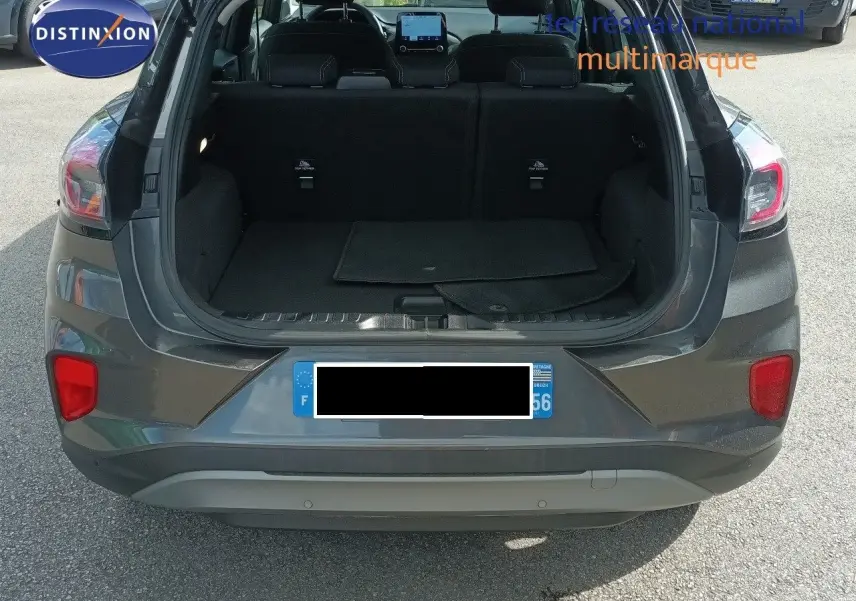 Vue arrière du Ford Puma gris foncé métal 2023 avec coffre ouvert montrant l’espace de chargement vide.