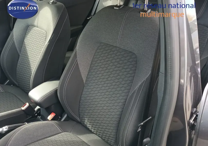 Gros plan sur les sièges avant en tissu gris foncé avec surpiqûres blanches du Ford Puma 2023, porte ouverte côté droit.