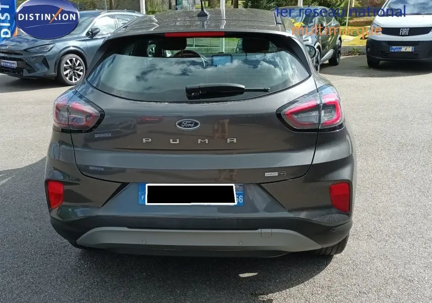 Vue arrière d'une Ford Puma gris foncé métal 2023 avec feux LED et logo bien visibles sur un parking extérieur.