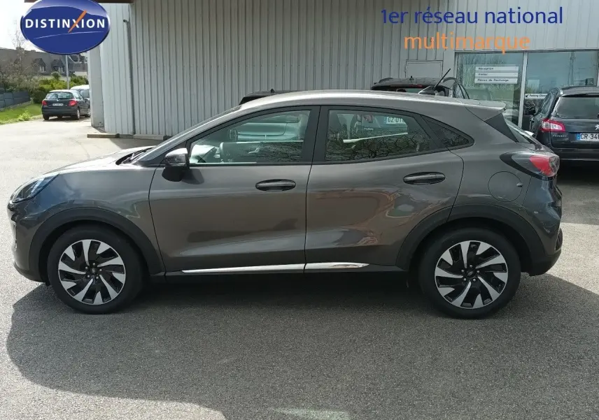 Vue latérale droite d'un Ford Puma gris foncé métallisé, soulignant ses jantes bicolores et sa silhouette compacte.