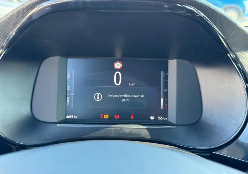 Gros plan sur le tableau de bord numérique de l’Opel Corsa rouge, affichant la vitesse à 0 km/h et divers indicateurs.