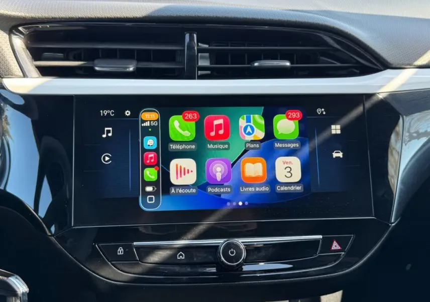 Écran tactile central de l’Opel Corsa rouge 2025 affichant Apple CarPlay avec icônes colorées, vue frontale rapprochée.