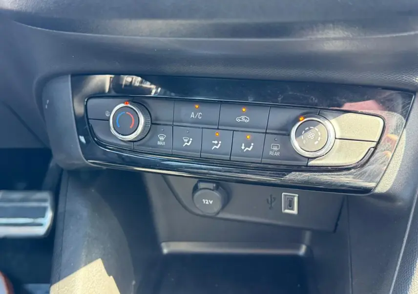 Gros plan sur la console centrale de la climatisation manuelle de l’Opel Corsa 2025, avec boutons et ports USB visibles.
