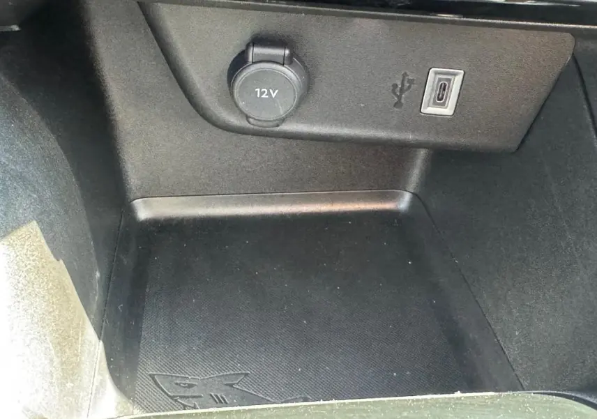 Gros plan sur la prise 12V et port USB-C dans le compartiment de rangement intérieur de l’Opel Corsa rouge.